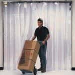 A person taking a dolly of boxes through a strip curtain door.