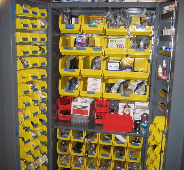 Yellow plastic stackable bins in a cabinet with materials stored inside.