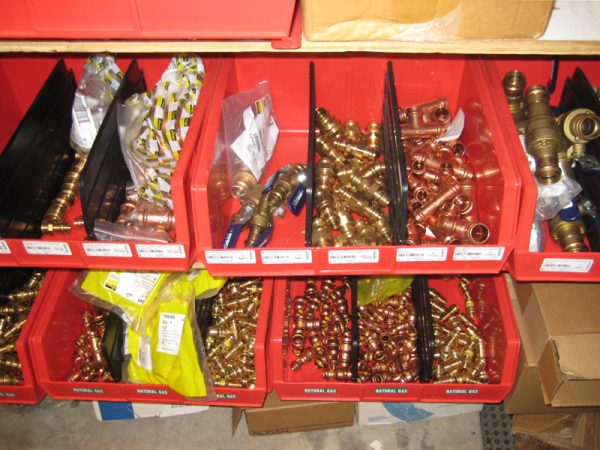 Several red plastic stackable bins storing parts in a warehouse setting.