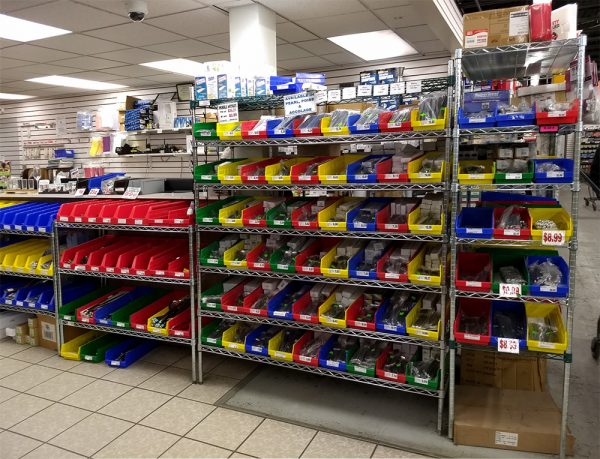 Multicolour plastic shelf bins storing materials on shelving in a warehouse setting.