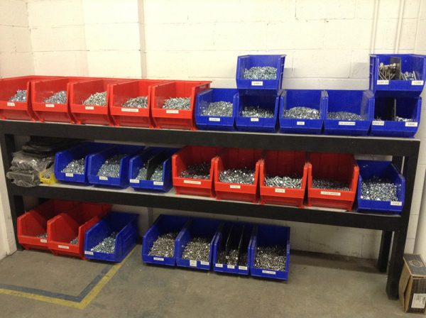 Extra large plastic bins on shelving holding parts on a white background.