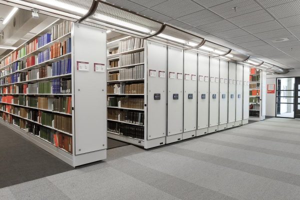 White powered mobile shelving in a library holding books.