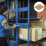 Manual mobile storage shelving with a person moving it in a warehouse setting.